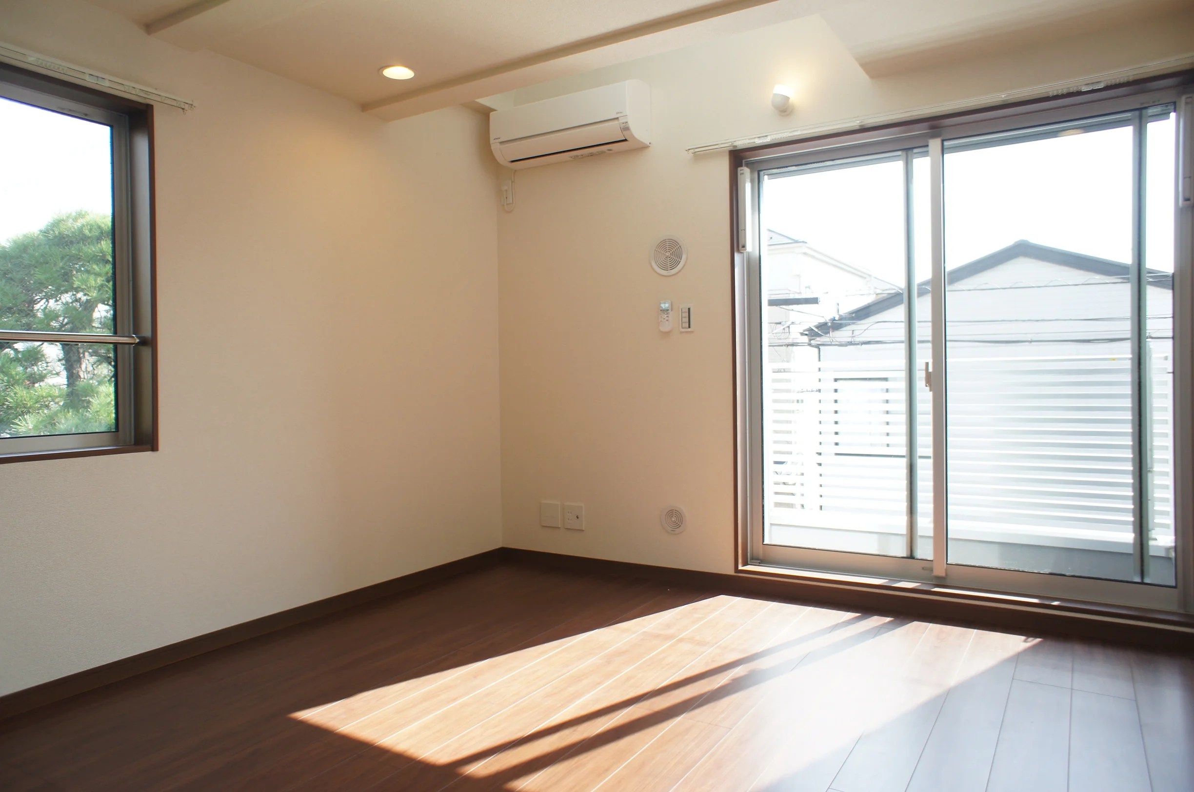 木目の床と白い壁で整えられた賃貸住宅の居室から窓辺を望む室内