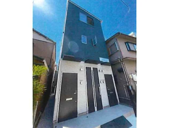黒いドアと白い外壁が印象的な3階建て賃貸住宅の外観